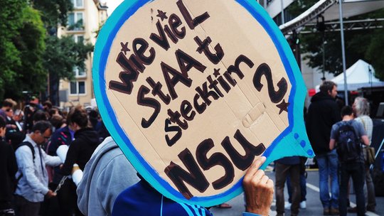 Ein Mann, der ein Schild hochhält, auf dem steht: Wie viel Staat steckt im NSU?