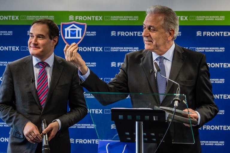 Dimitris Avramopoulos holding up a photoshopped FragDenStaat Logo, next to Fabrice Leggeri