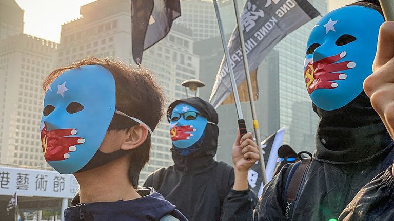Menschen protestieren in China mit Masken mit der in China verbotenen „Ostturkestanflagge“