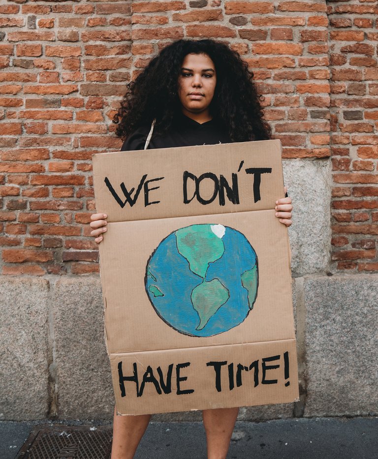 Eine Frau hält Kartonschild, bemalt mit einer Erde und dem Text "We don't have time!"
